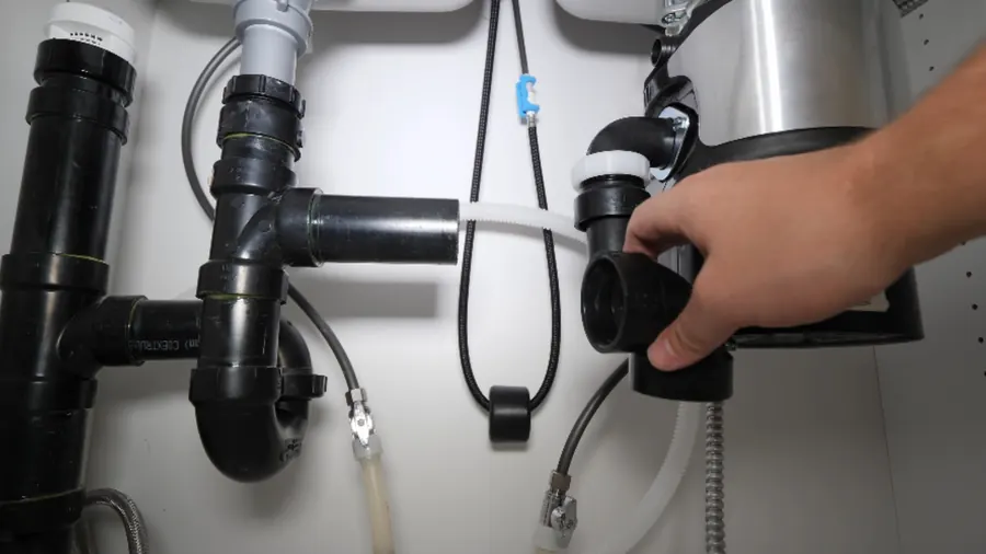 Garbage disposal mounted under a kitchen sink with drain and power connections
